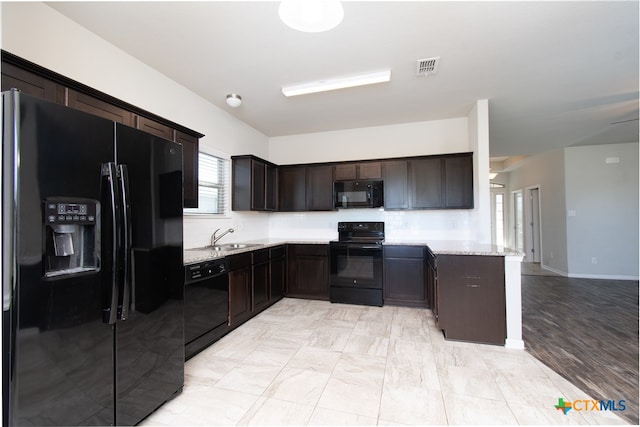 kitchen featuring dark brown cabinets, sink, light stone counters, and black appliances