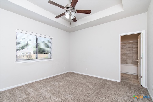 carpeted empty room featuring a raised ceiling and ceiling fan