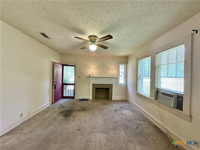 1015 N 3rd St, Temple, TX 76501 - unfurnished living room featuring a textured ceiling, carpet flooring, plenty of natural light, a ceiling fan, and a brick fireplace
