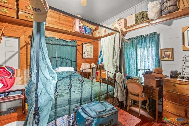 bedroom with wood walls and wood finished floors