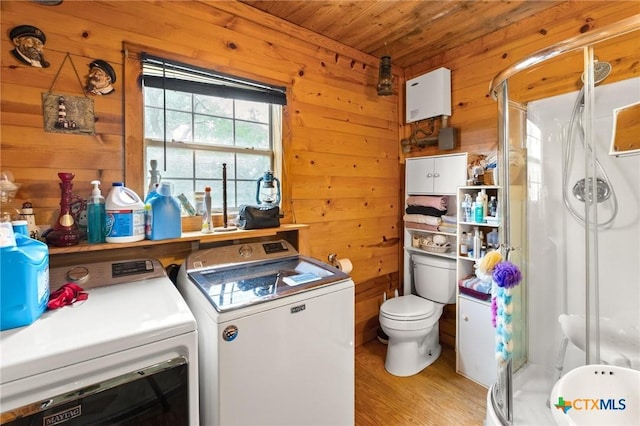 clothes washing area featuring independent washer and dryer, laundry area, wooden ceiling, wooden walls, and light wood-style floors