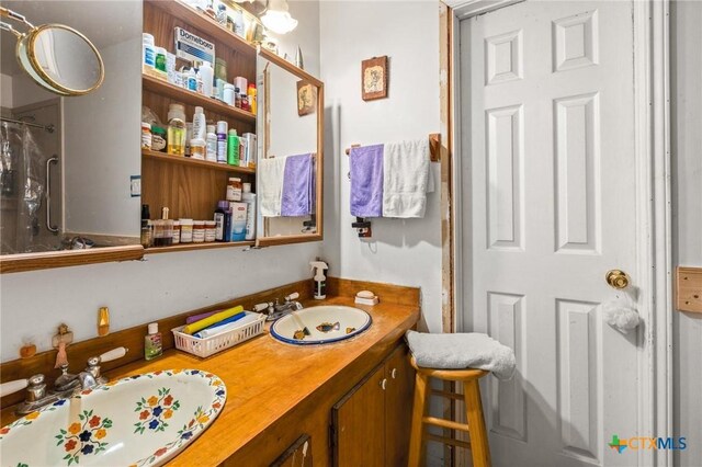full bath featuring walk in shower, double vanity, and a sink