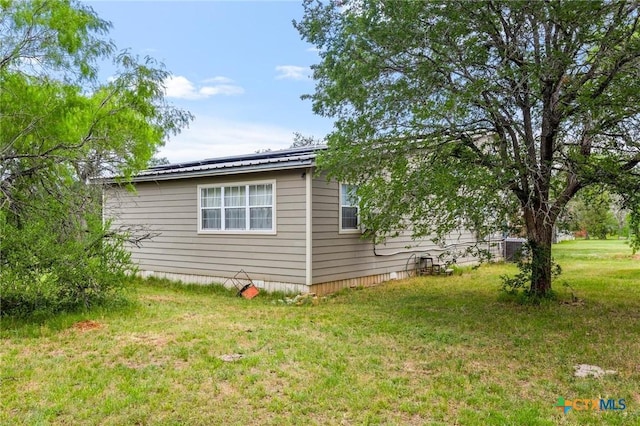view of side of home with metal roof and a lawn