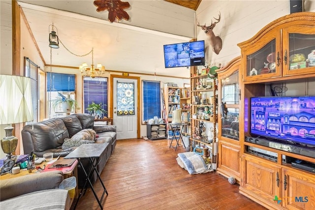 living area featuring dark wood finished floors, wood walls, a healthy amount of sunlight, and a notable chandelier
