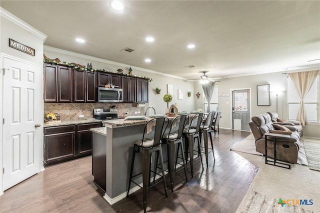 8907 Misty Pine Dr, Temple, TX 76502 - kitchen featuring appliances with stainless steel finishes, a ceiling fan, a breakfast bar, a kitchen island with sink, and crown molding