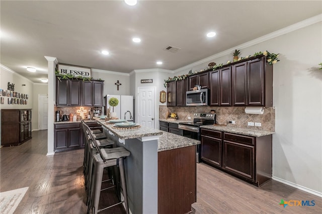 8907 Misty Pine Dr, Temple, TX 76502 - kitchen featuring stainless steel appliances, dark brown cabinetry, dark wood-style floors, ornamental molding, and decorative backsplash