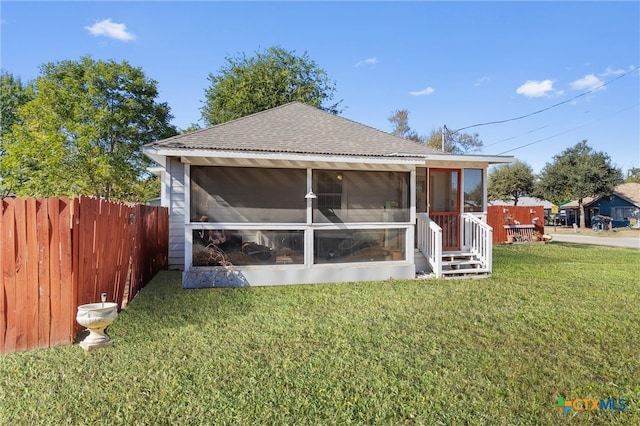 back of property featuring a lawn and a sunroom