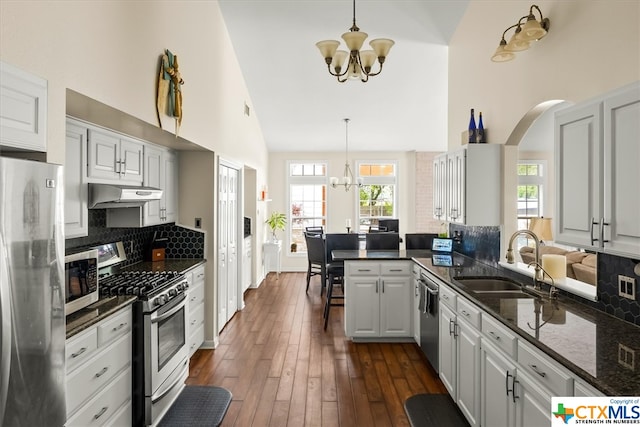 kitchen with extractor fan, appliances with stainless steel finishes, hanging light fixtures, and white cabinets