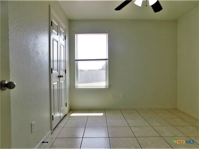 tiled empty room featuring ceiling fan