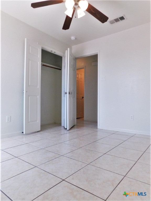 unfurnished bedroom featuring a closet, light tile patterned flooring, and ceiling fan