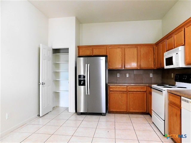 kitchen featuring tasteful backsplash, white appliances, and light tile patterned flooring