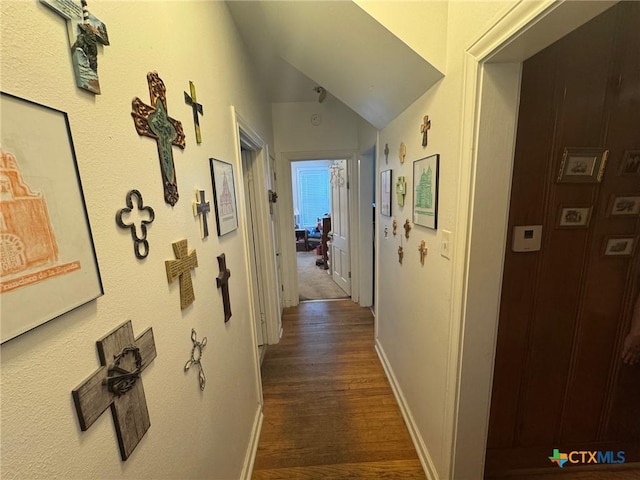 hallway with baseboards, dark wood-style flooring, and lofted ceiling