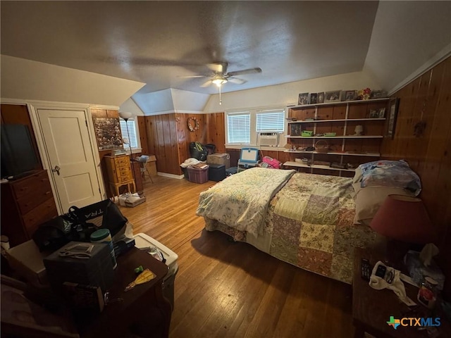 bedroom featuring cooling unit, lofted ceiling, a ceiling fan, wood finished floors, and wooden walls