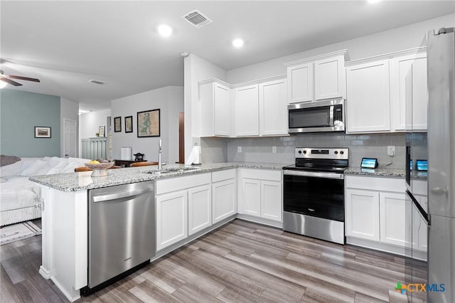 2512 Corradino St, Harker Heights, TX 76548 - kitchen with appliances with stainless steel finishes, open floor plan, a sink, white cabinetry, and light wood-style floors