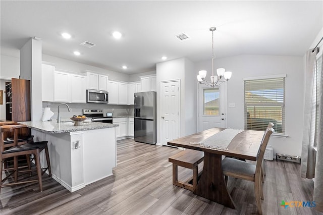 2512 Corradino St, Harker Heights, TX 76548 - kitchen with stainless steel appliances, a peninsula, light wood finished floors, a chandelier, and recessed lighting