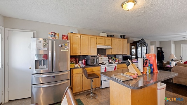 kitchen with a center island, under cabinet range hood, stainless steel appliances, and a textured ceiling