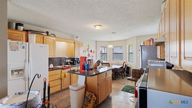 kitchen featuring under cabinet range hood, dark countertops, visible vents, a kitchen island, and white fridge with ice dispenser