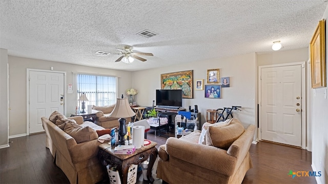 living room featuring a textured ceiling, dark wood finished floors, baseboards, visible vents, and ceiling fan