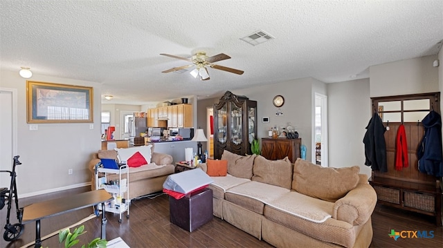 living room with a textured ceiling, baseboards, visible vents, ceiling fan, and dark wood-type flooring