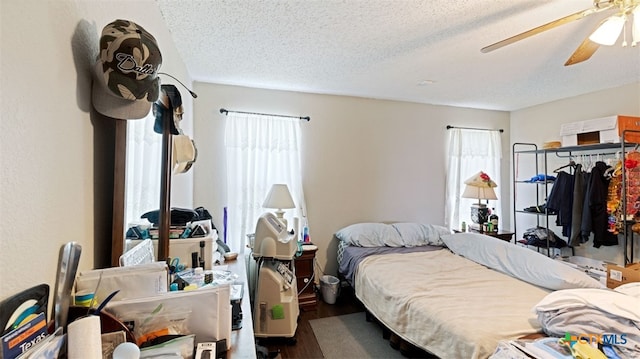 bedroom with a ceiling fan, wood finished floors, and a textured ceiling