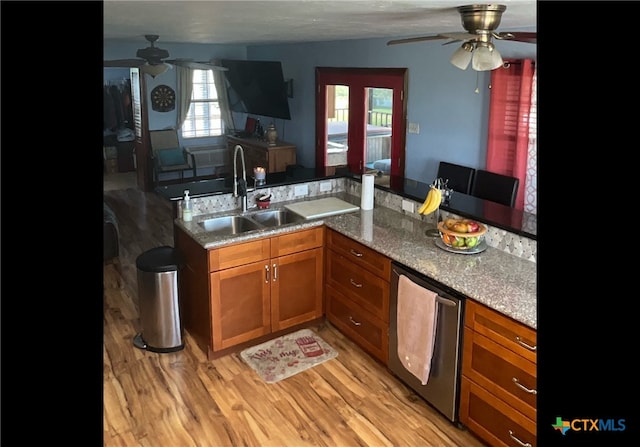 kitchen with light wood-type flooring, stone counters, sink, kitchen peninsula, and ceiling fan