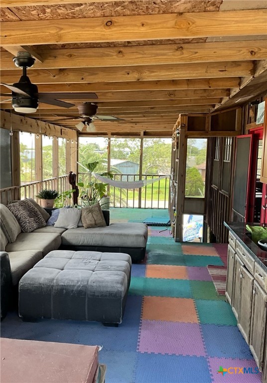 sunroom with ceiling fan and beam ceiling