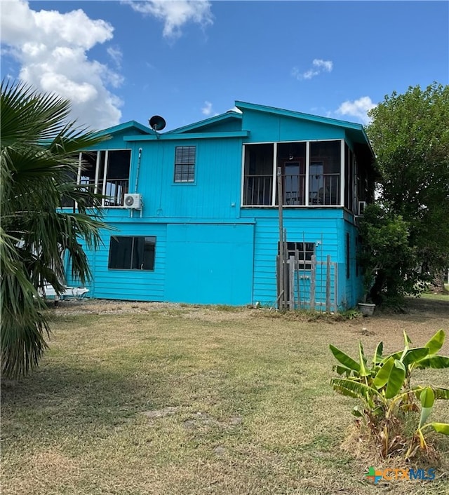 back of property with a lawn and a sunroom