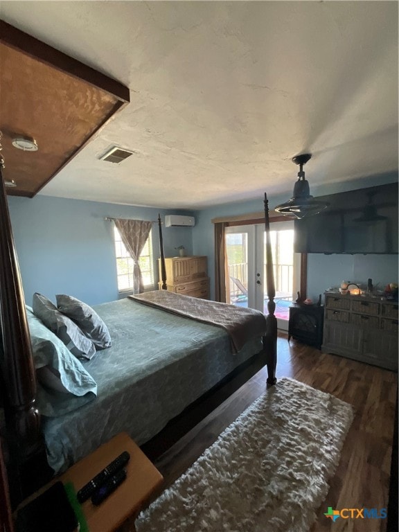 bedroom featuring access to outside, dark hardwood / wood-style flooring, multiple windows, and a wall mounted air conditioner