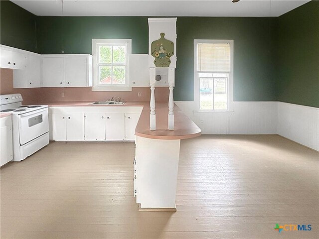307 N Pecan St, Moulton, TX 77975 - kitchen featuring white electric stove, light wood finished floors, a wainscoted wall, and white cabinets