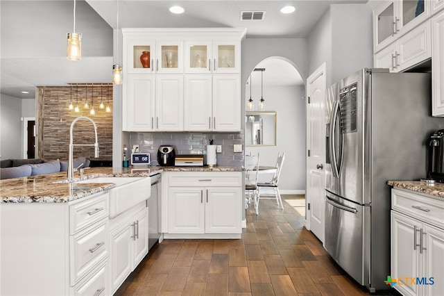 kitchen featuring visible vents, decorative backsplash, appliances with stainless steel finishes, a peninsula, and a sink