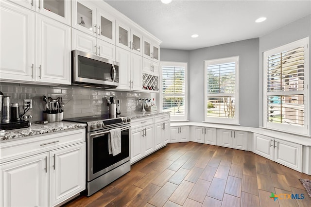 kitchen featuring white cabinetry, dark wood-style floors, tasteful backsplash, and stainless steel appliances