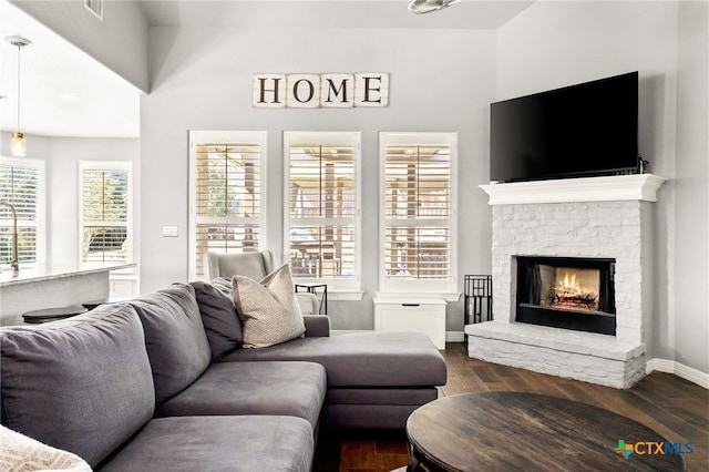 living area with dark wood finished floors, a fireplace, and baseboards