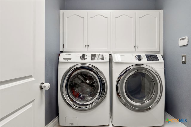 washroom with cabinet space and washing machine and clothes dryer