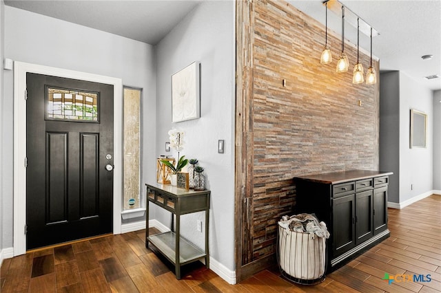 foyer entrance with dark wood-style floors and baseboards