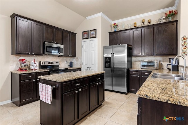 kitchen with dark brown cabinetry, sink, stainless steel appliances, backsplash, and a kitchen island