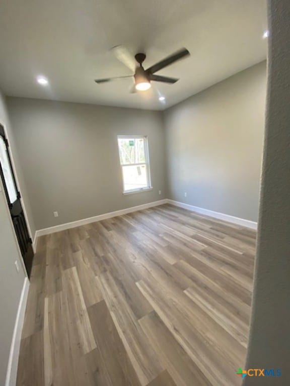 empty room featuring recessed lighting, wood finished floors, baseboards, and ceiling fan