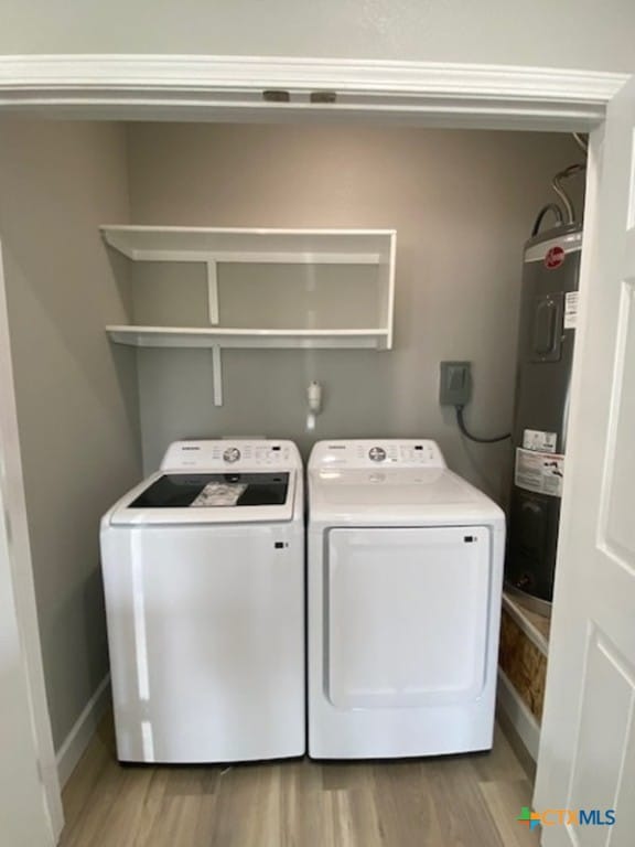 laundry area featuring laundry area, washer and dryer, electric water heater, and light wood-type flooring