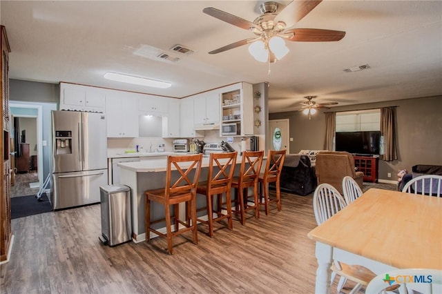 kitchen featuring stainless steel appliances, visible vents, white cabinetry, and wood finished floors