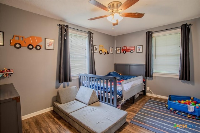 bedroom with baseboards, wood finished floors, and multiple windows