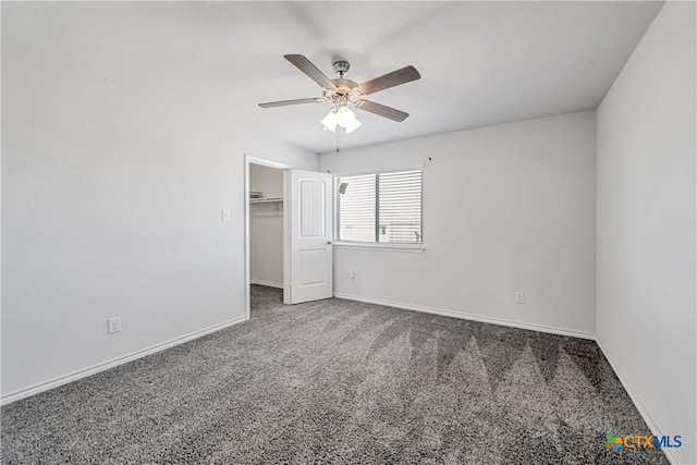 unfurnished bedroom with ceiling fan, baseboards, carpet floors, and a walk in closet