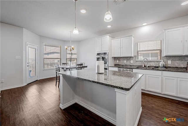 kitchen with tasteful backsplash, visible vents, dark wood-style flooring, stainless steel appliances, and a sink