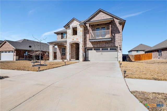 view of front of home with a balcony, fence, driveway, stone siding, and brick siding