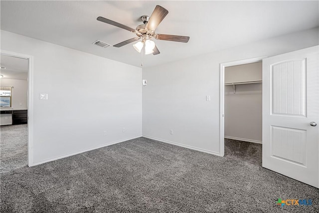 unfurnished bedroom with a ceiling fan, carpet, visible vents, baseboards, and a walk in closet