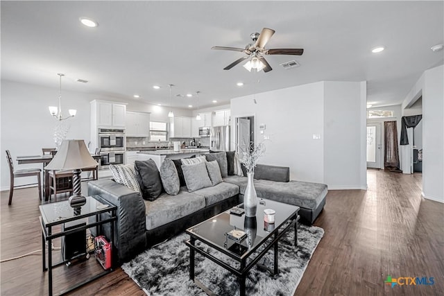 living room with ceiling fan with notable chandelier, recessed lighting, wood finished floors, and visible vents