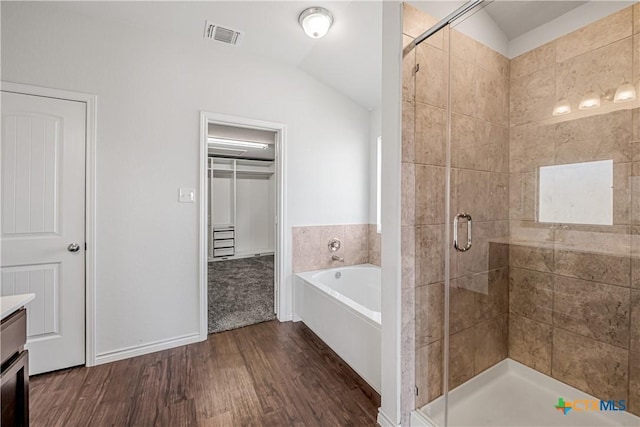 bathroom with visible vents, lofted ceiling, a garden tub, a stall shower, and wood finished floors