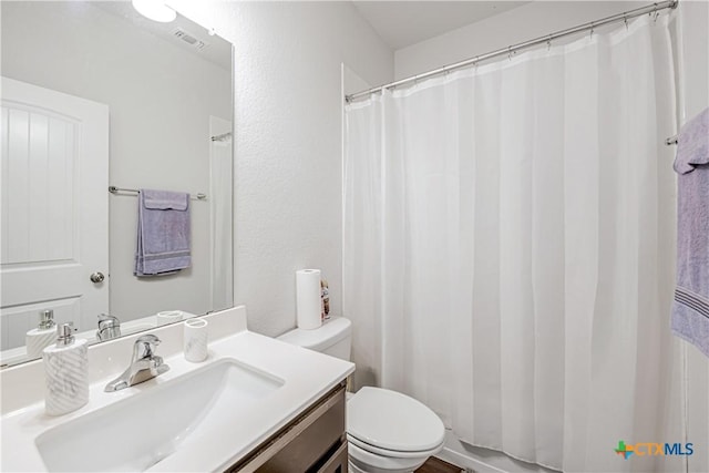 bathroom featuring vanity, toilet, and visible vents