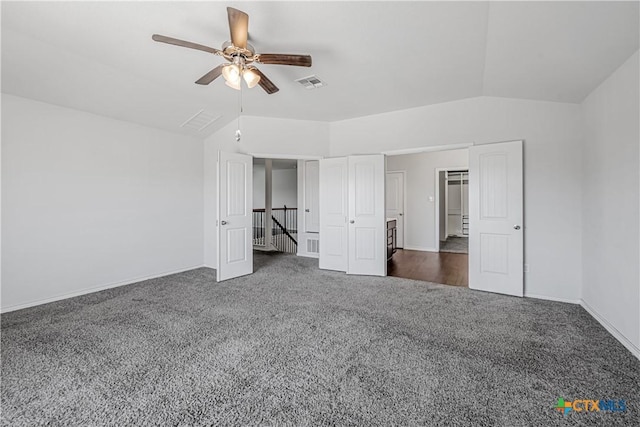 unfurnished bedroom with visible vents, baseboards, ceiling fan, dark carpet, and vaulted ceiling