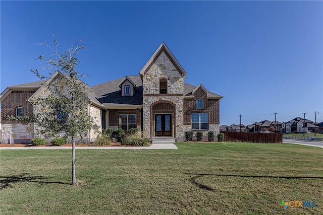 french provincial home featuring a front yard and french doors