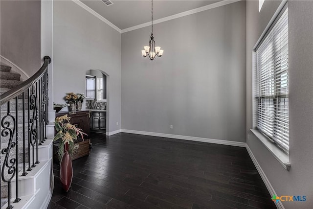 entrance foyer with dark hardwood / wood-style flooring, an inviting chandelier, and crown molding