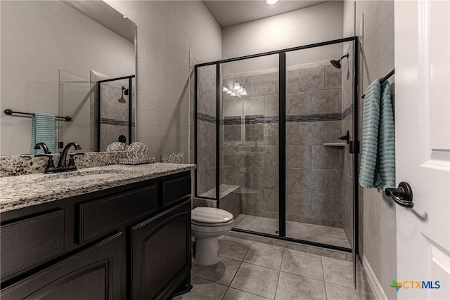 bathroom featuring toilet, vanity, tile patterned floors, and a shower with door